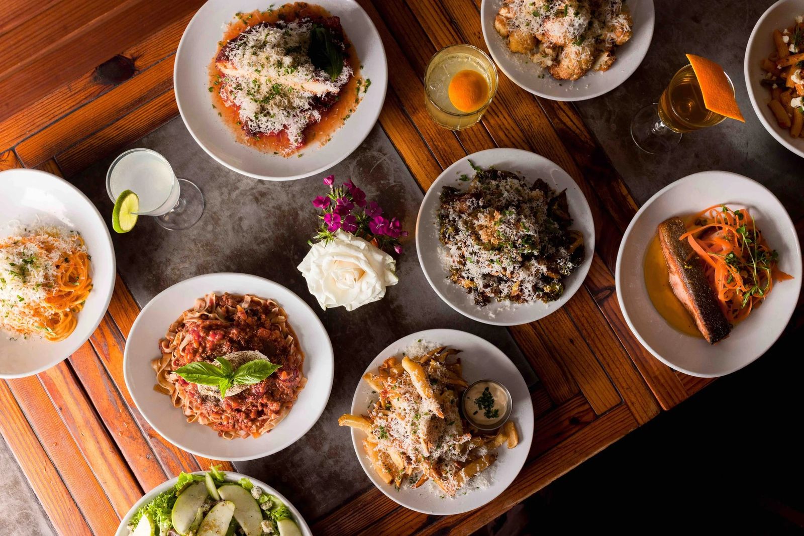 Overhead view of a wooden table covered with plates of pasta and small dishes