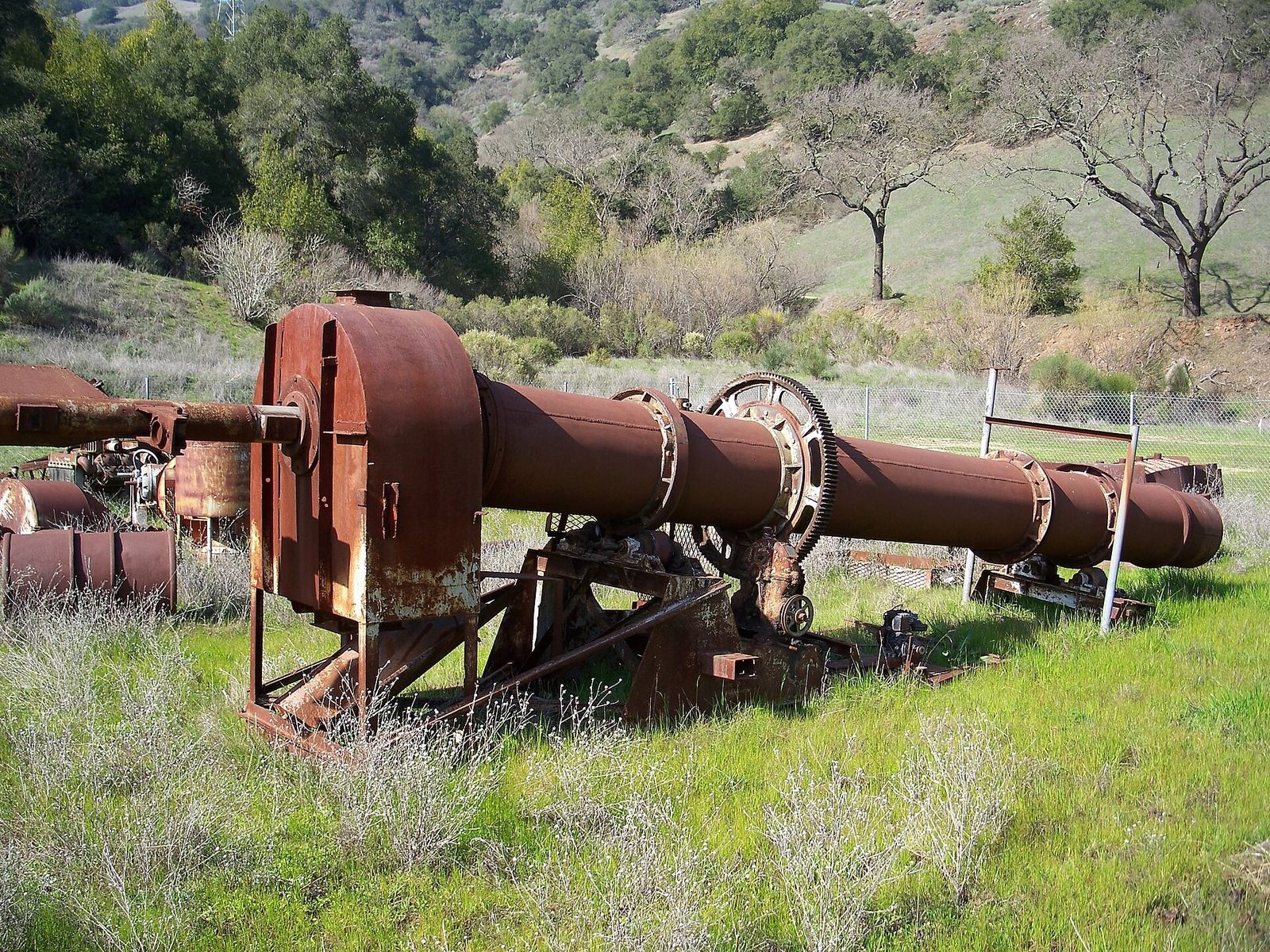 Rusted old mining machinery lying in a grassy hillside field