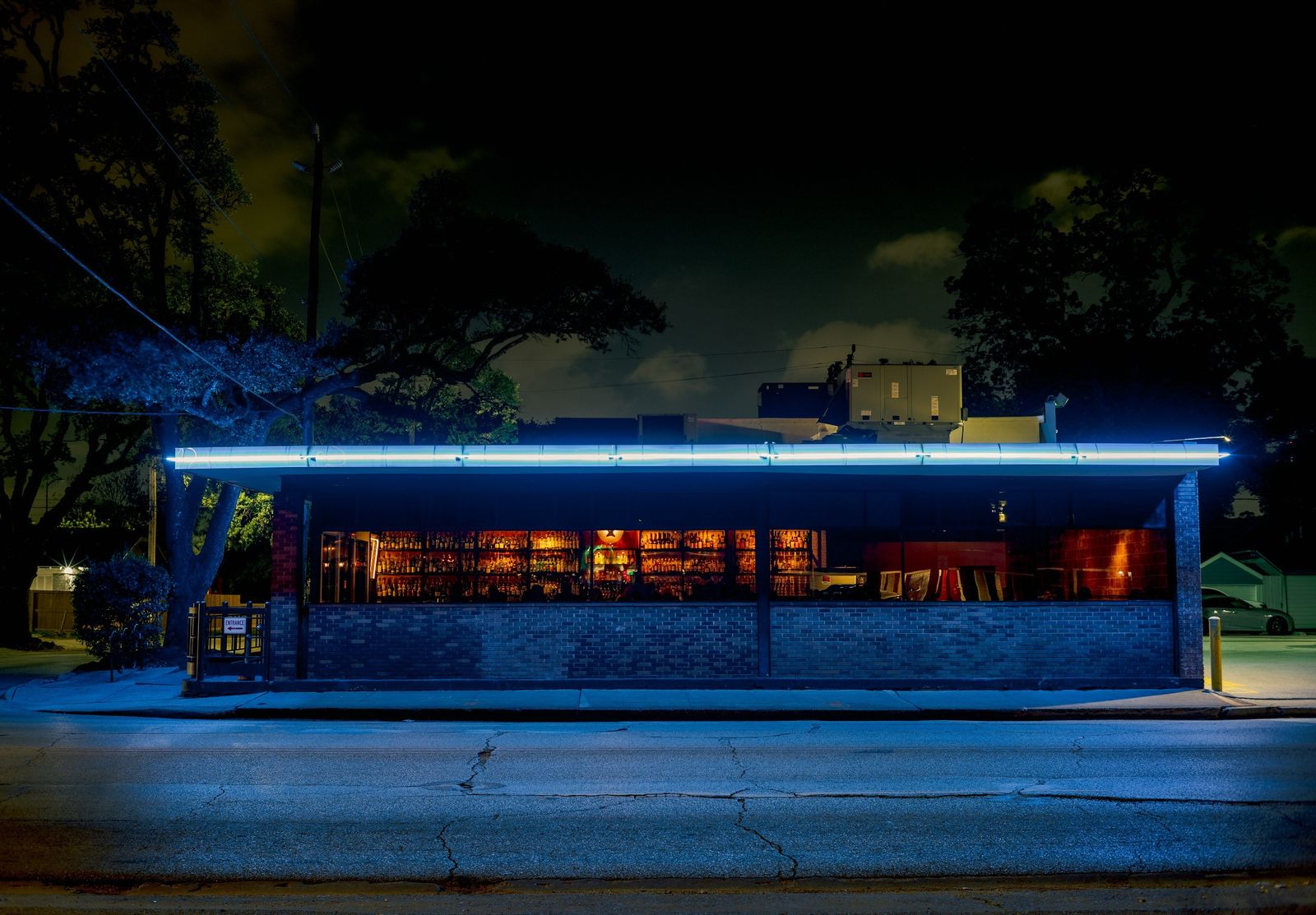 Low building with a glowing blue neon strip and lit windows at night