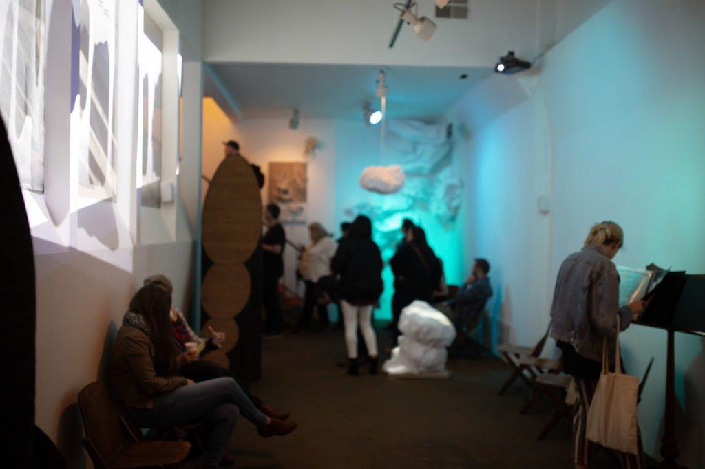 Visitors seated in a dimly lit room washed in teal light.