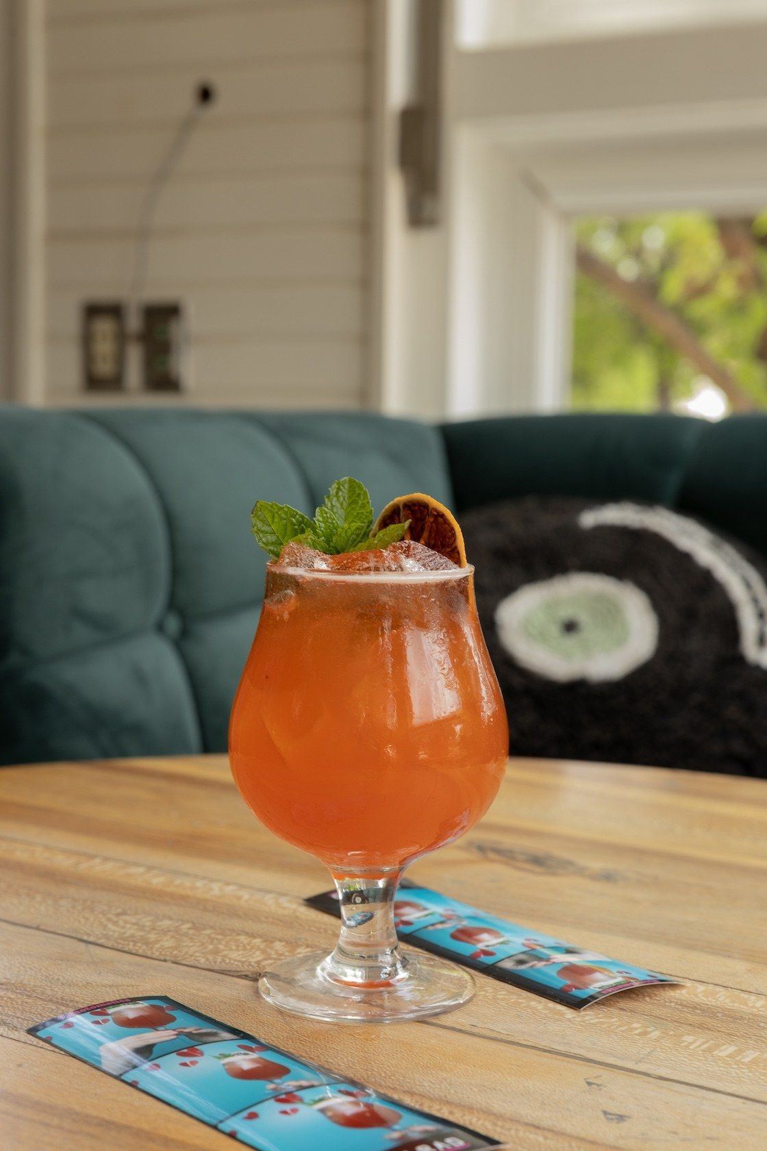 Orange cocktail in a stemmed glass garnished with mint on a wooden table