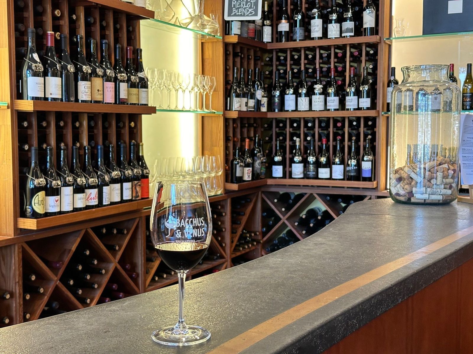 Tasting bar with a wine glass in front of wooden racks and shelves of bottles