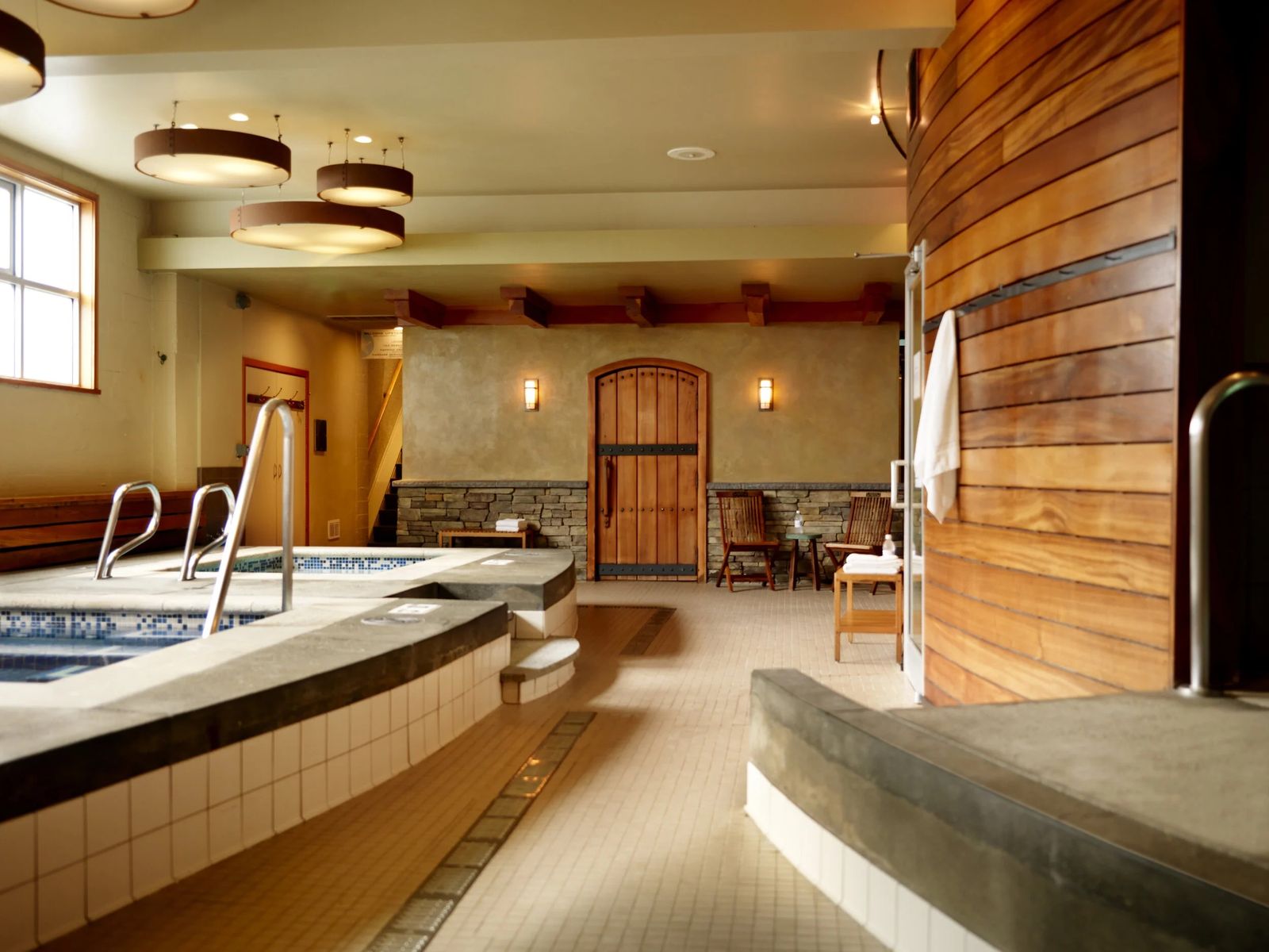 An indoor spa room with a plunge pool, wood-paneled walls and a stone bench along the edge.