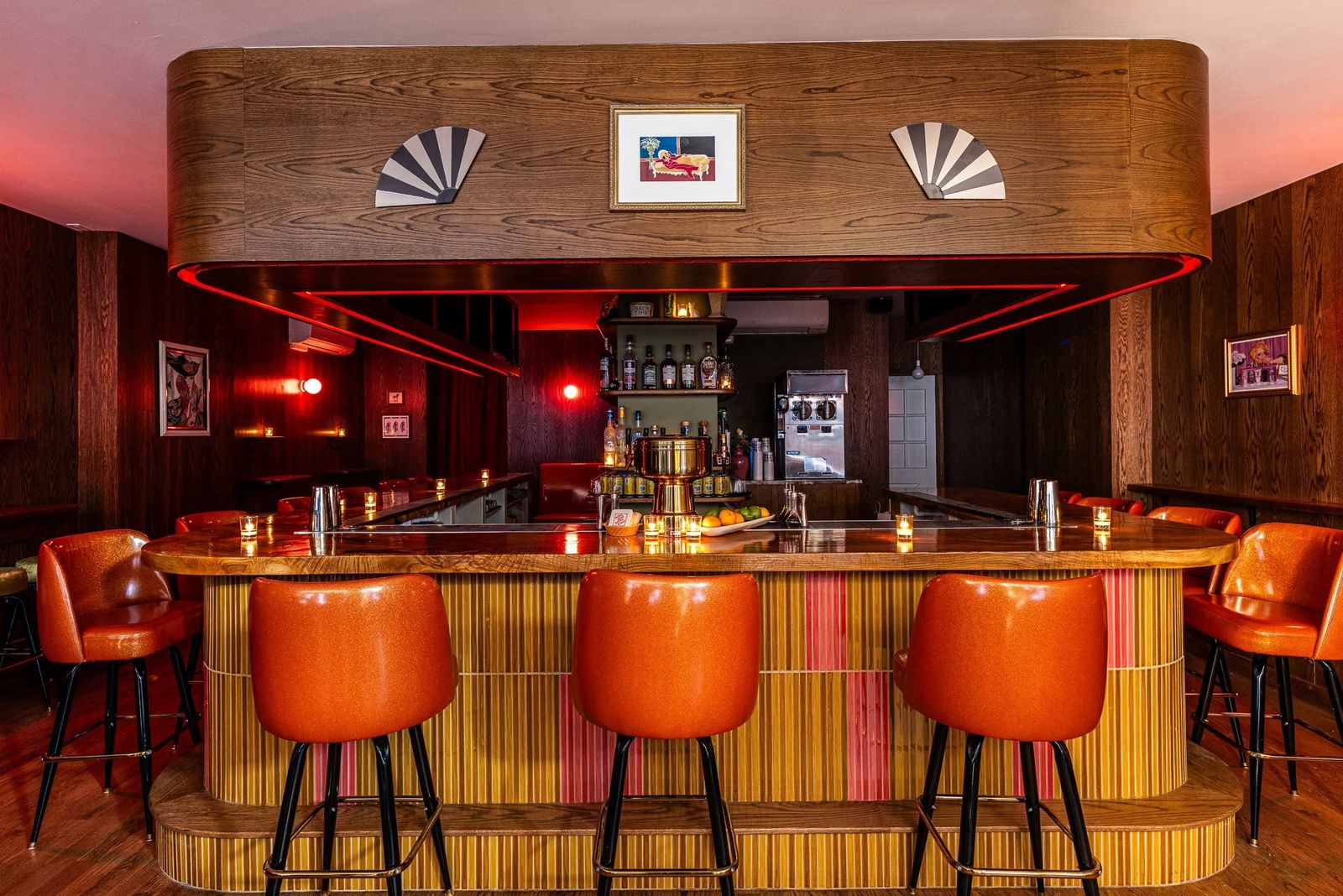 A wood-paneled bar with orange stools and a striped bar front