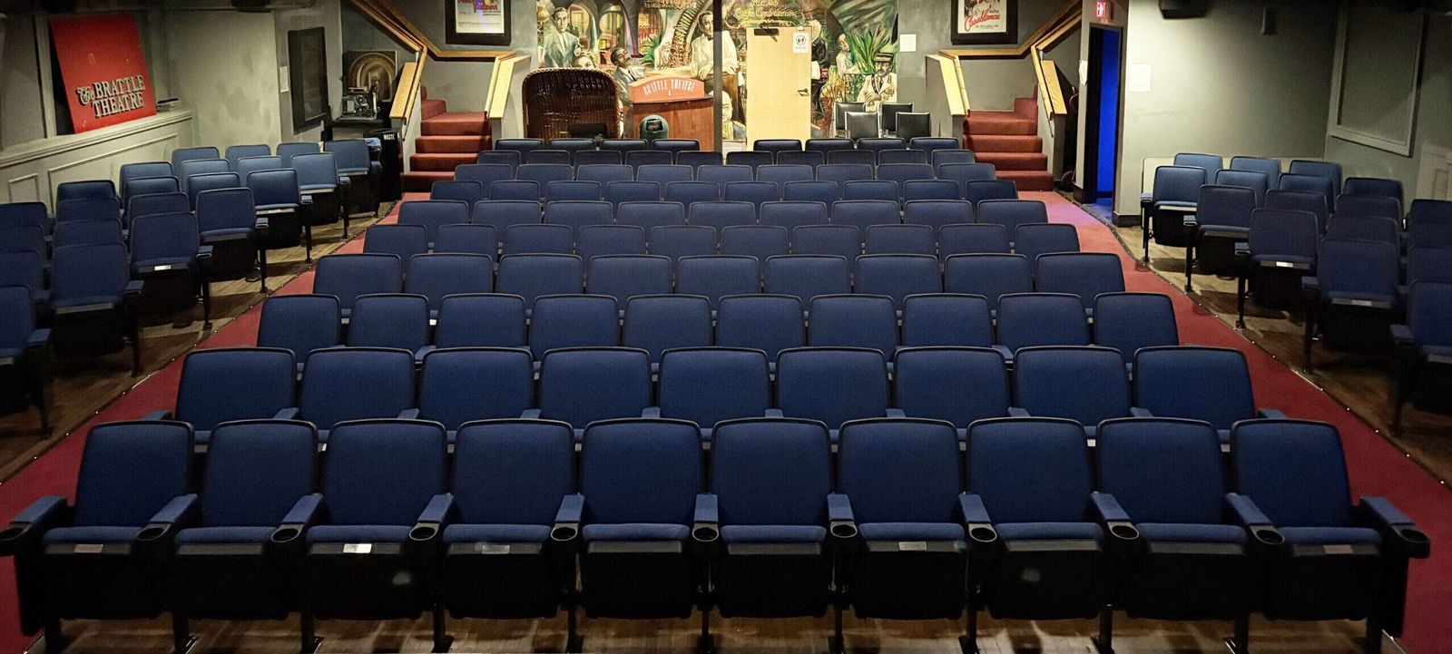Rows of blue seats in an empty auditorium facing a stage
