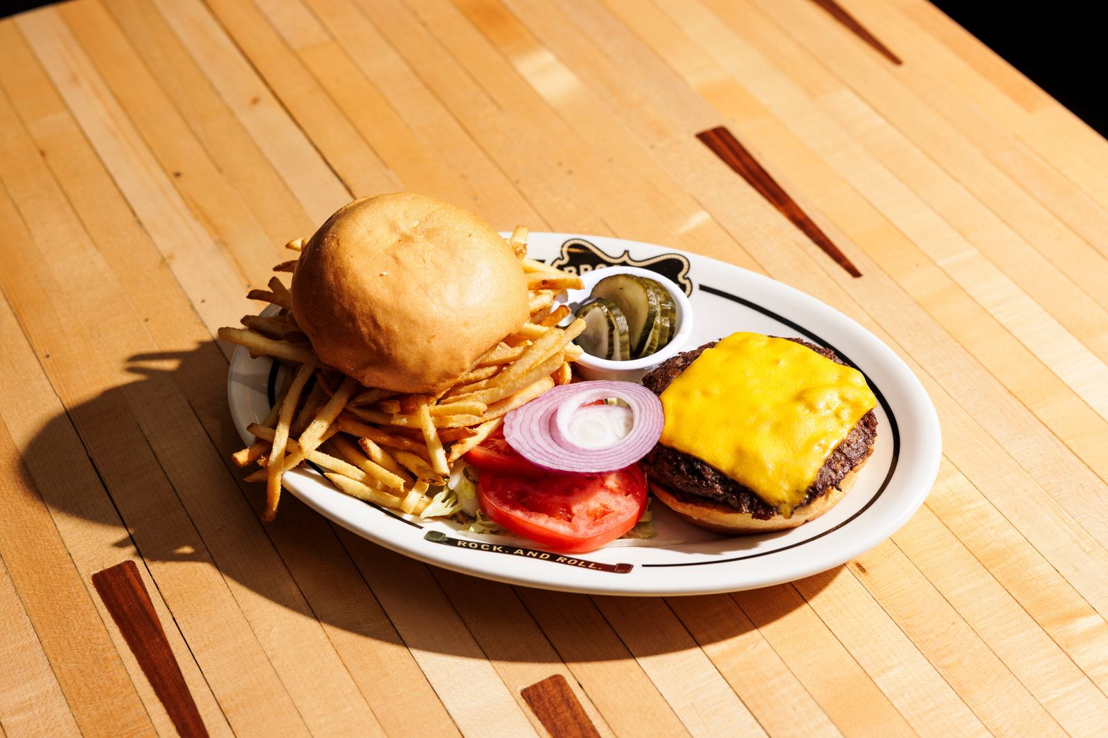 Cheeseburger and fries on a plate set on a bowling lane surface