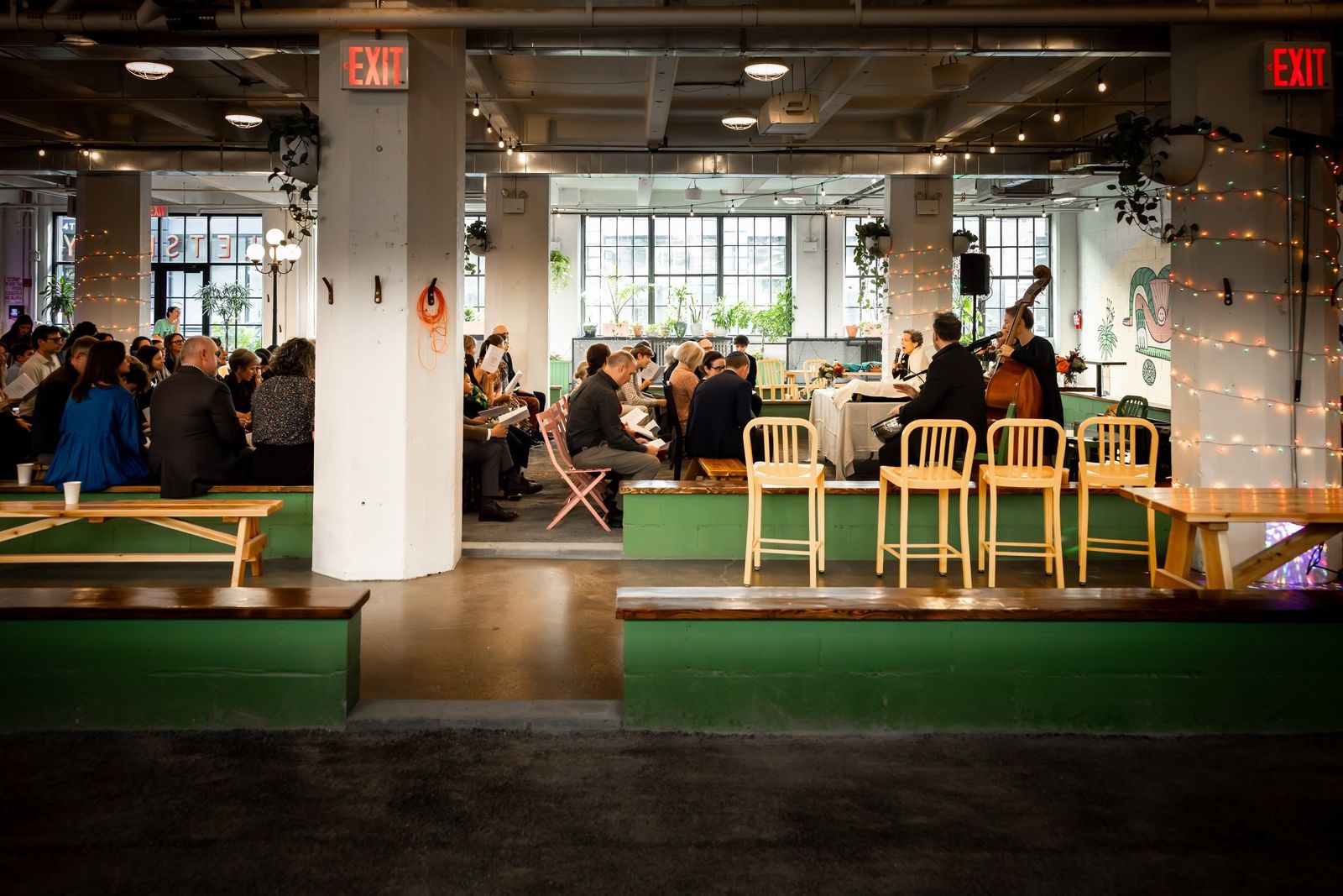 Wide view of the Carreau Club interior with petanque courts, bar stools and diners beneath string lights