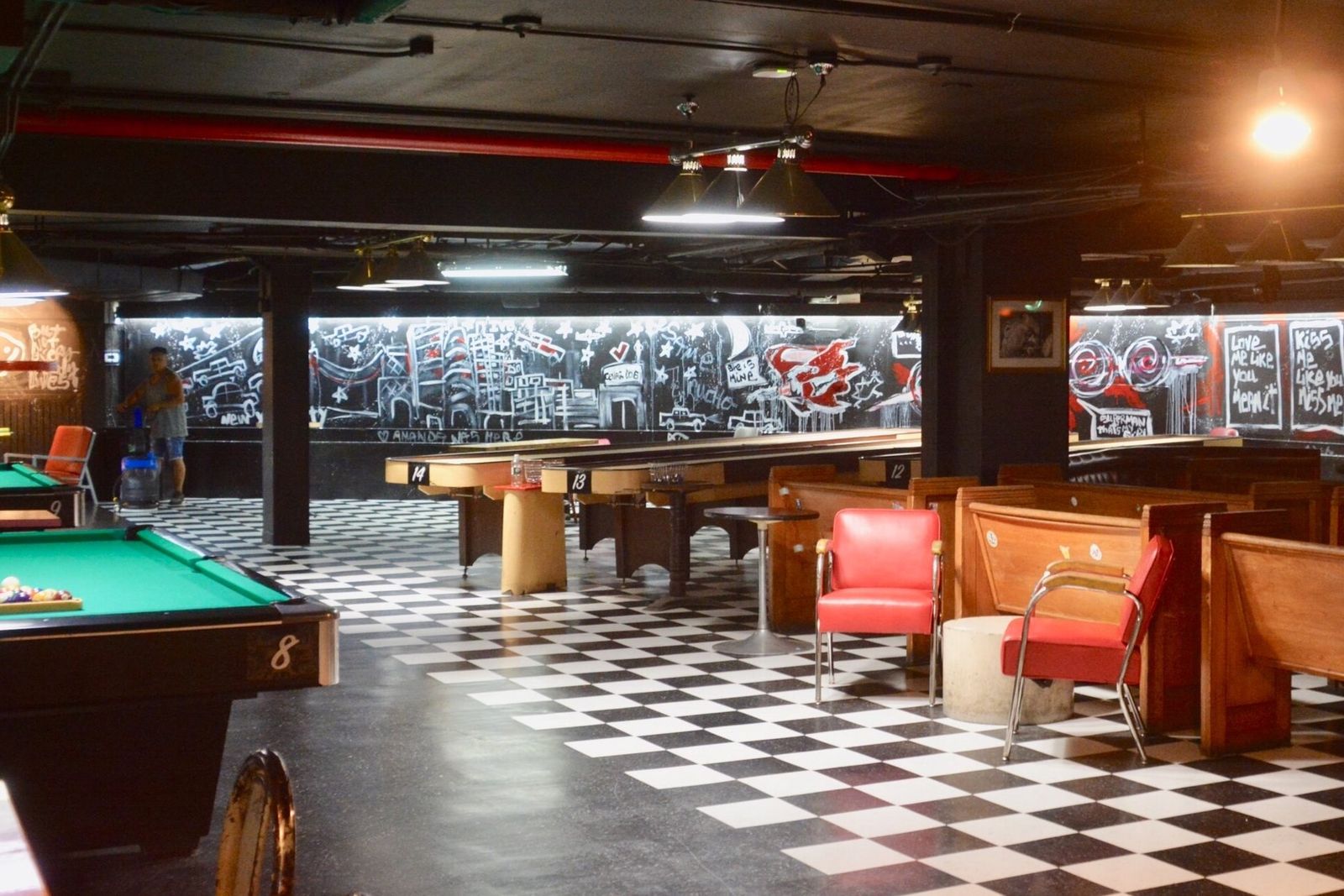 A pool hall interior with pool tables, booths and a checkerboard floor