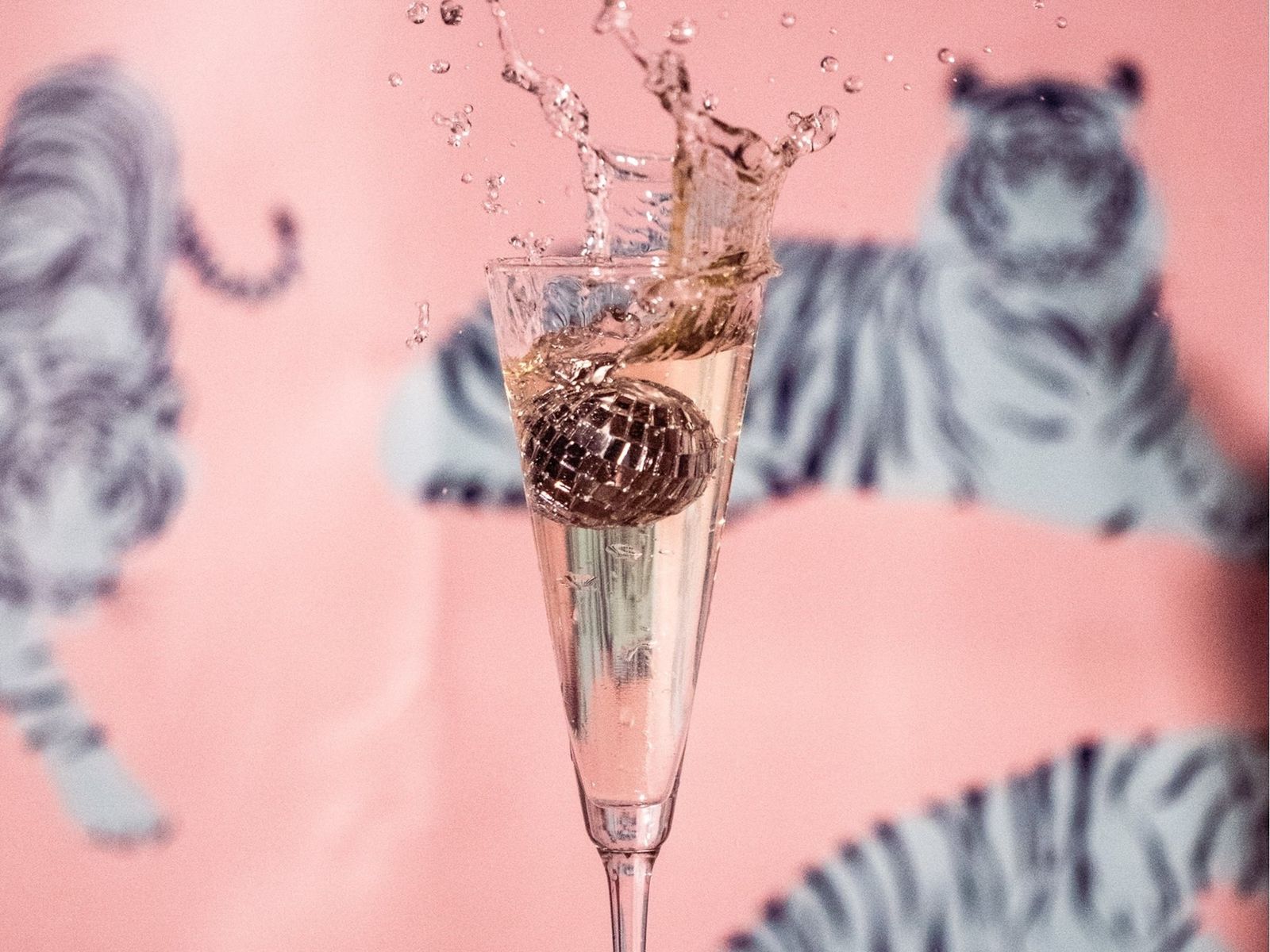 A champagne flute with a splash against a pink tiger-print backdrop