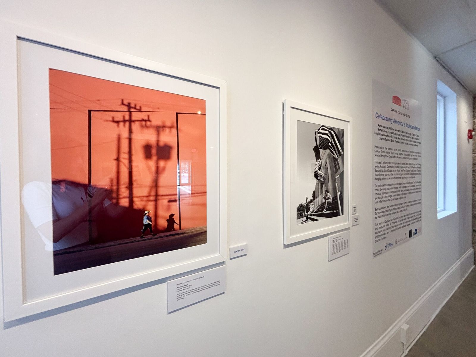 White gallery wall with framed photographs and a wall label