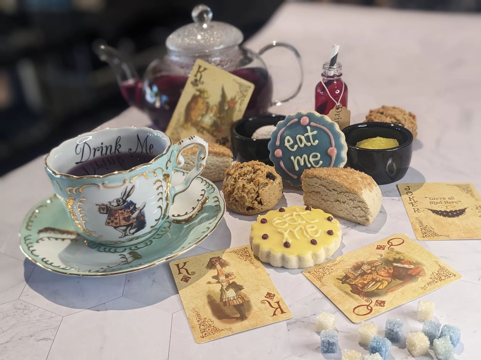 A decorated teacup with tea cookies and playing cards on a table