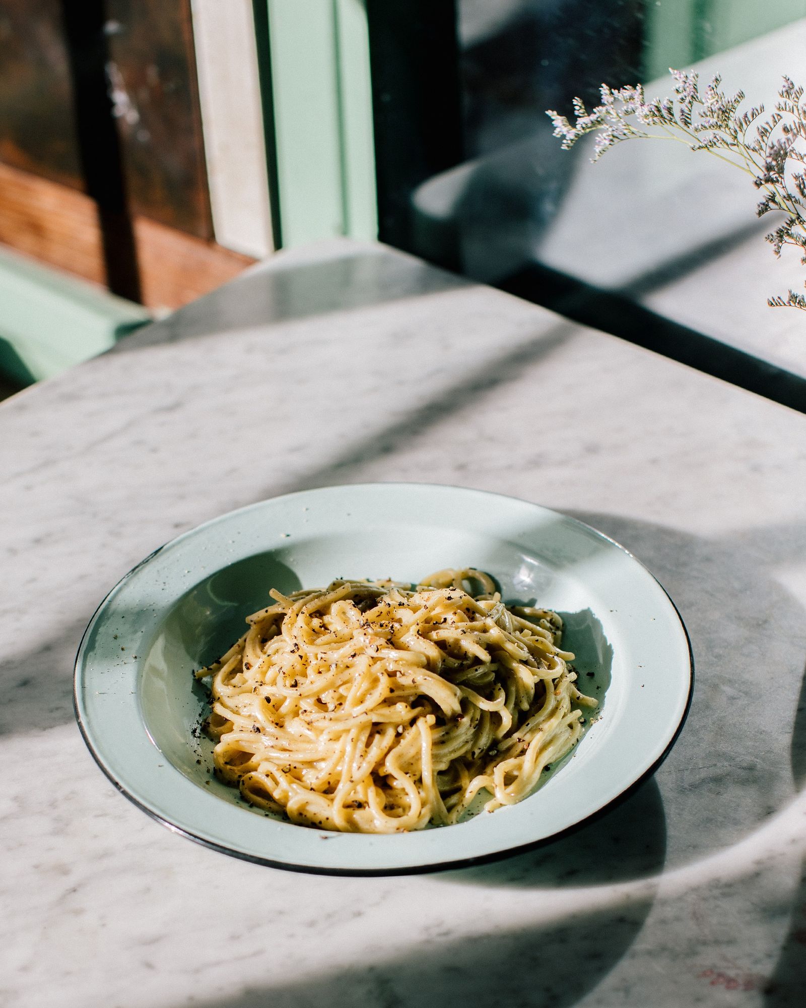Bowl of pasta on a marble table in window light