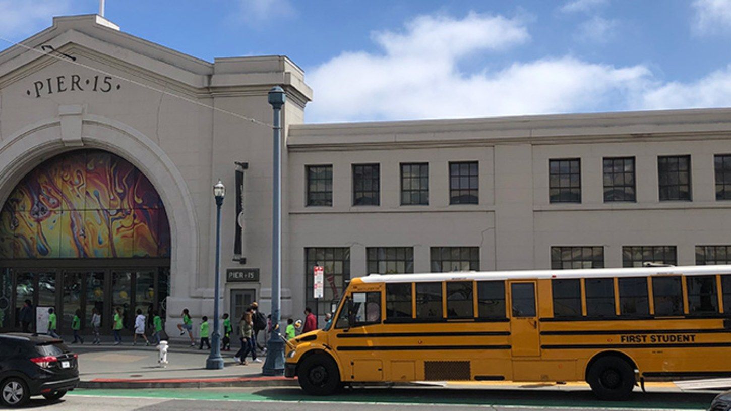 The pier-side exhibition hall's arched entrance and a yellow school bus parked outside.