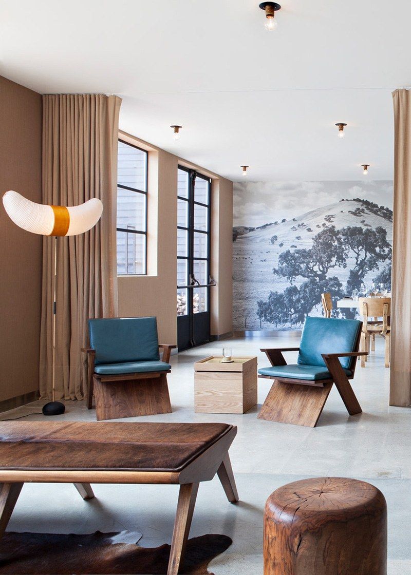 Lounge corner with leather chairs, a wood bench table and a large landscape mural