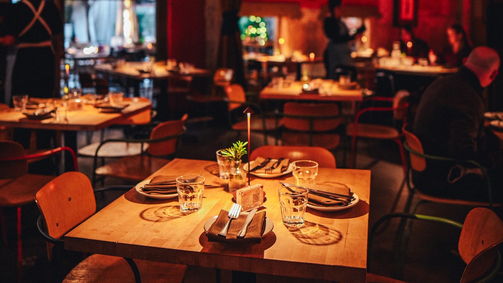 A candlelit restaurant table set with plates and glasses in a warmly lit dining room