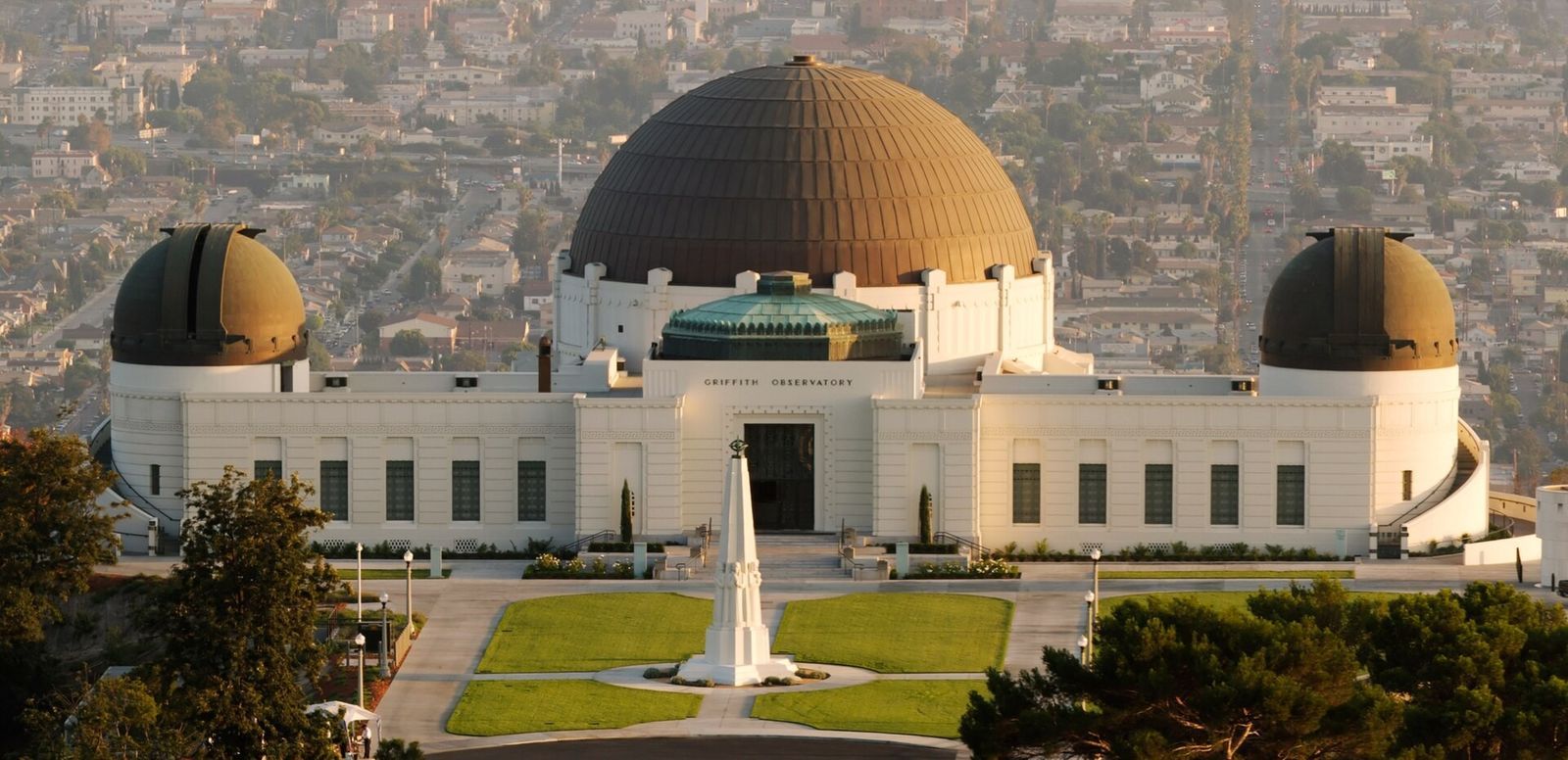 The domed observatory building and its lawn with a tall obelisk, seen from above with the city beyond.