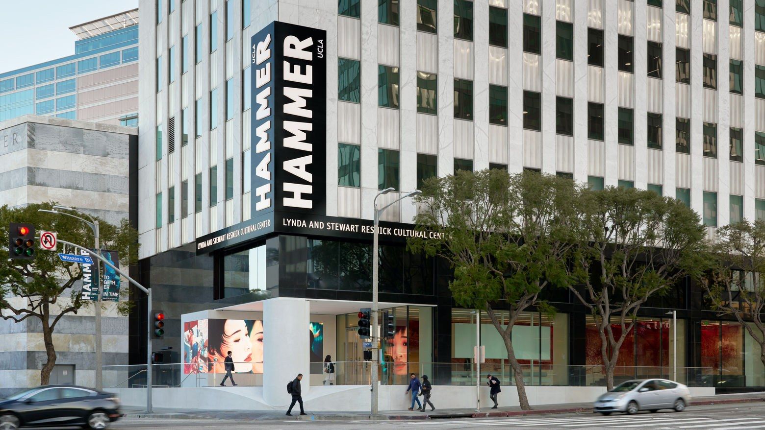A glass office building with a large vertical HAMMER sign over the museum entrance, on a street corner.