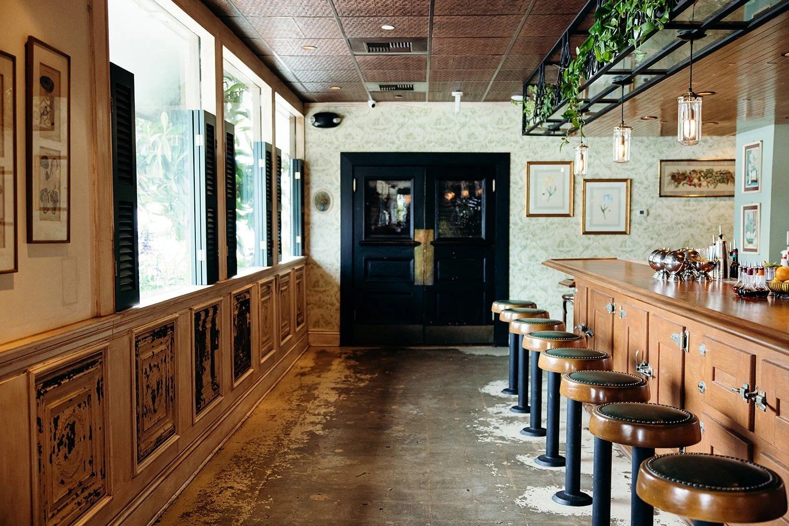 Long wood-paneled dining room with a bar and leather stools running along tall windows