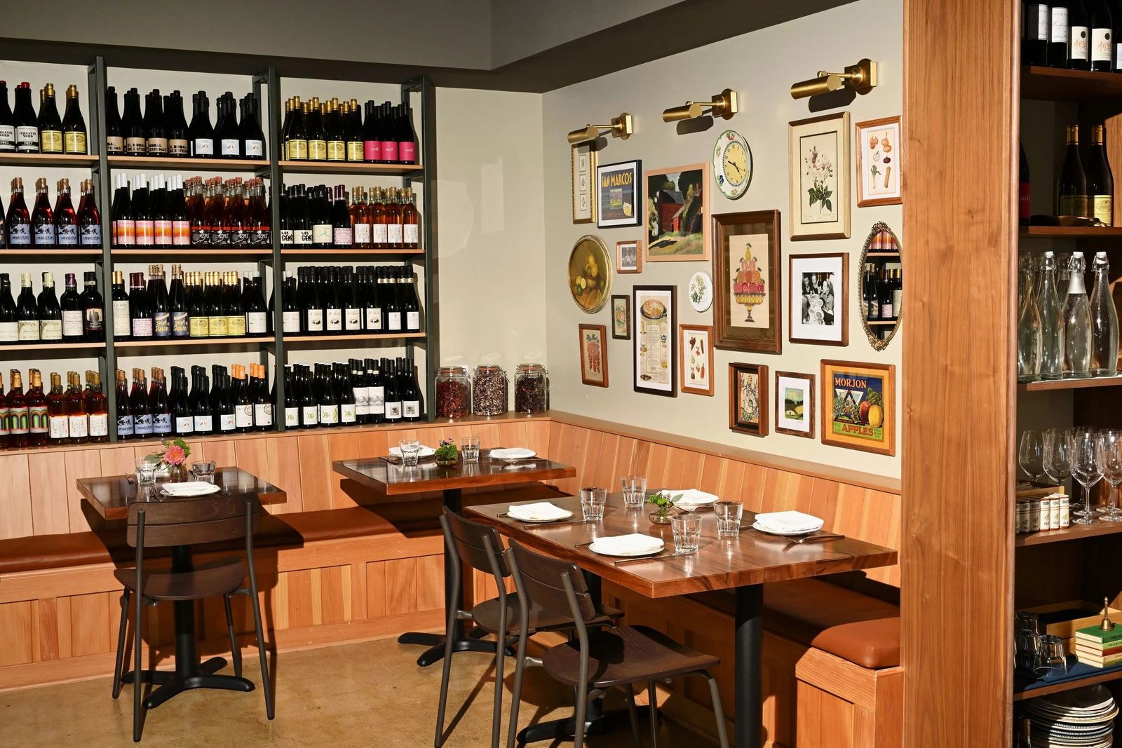 Dining room with wine shelves, framed pictures on the wall and wooden tables and chairs