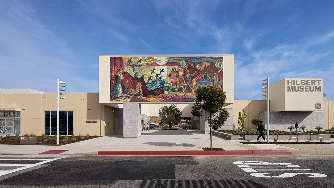 The museum's low building with a large mural above the entrance, under a blue sky.