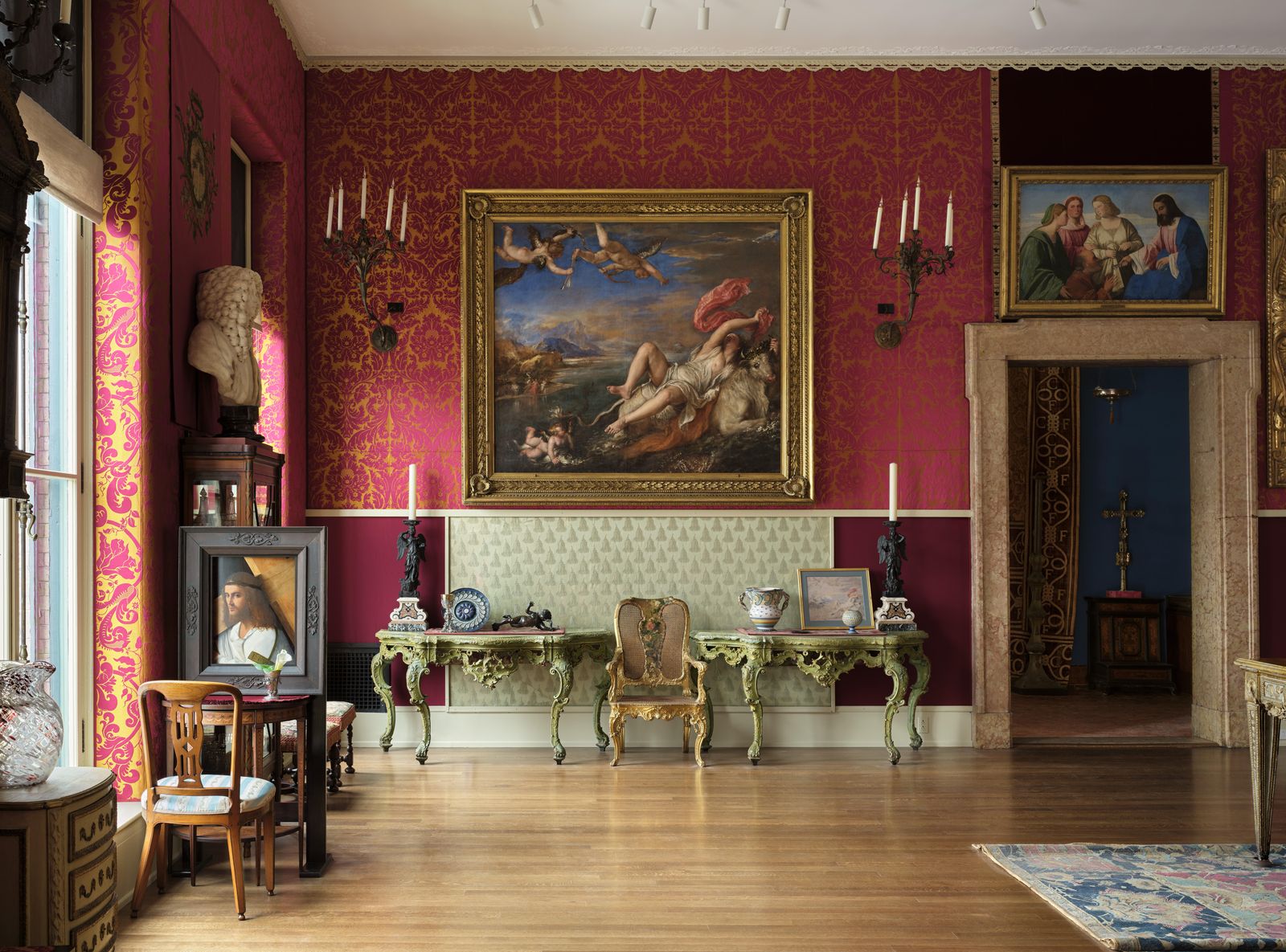 Gallery room with red damask walls, framed paintings and antique furniture