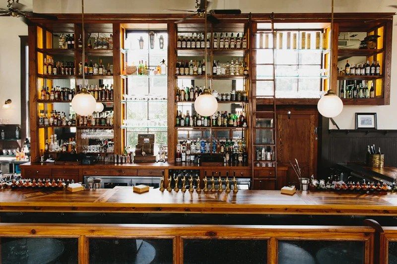 Wooden bar with shelves of bottles behind it