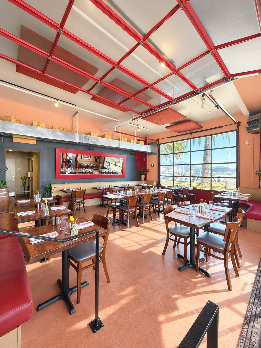 Bright dining room with red-framed ceiling, tables and large windows