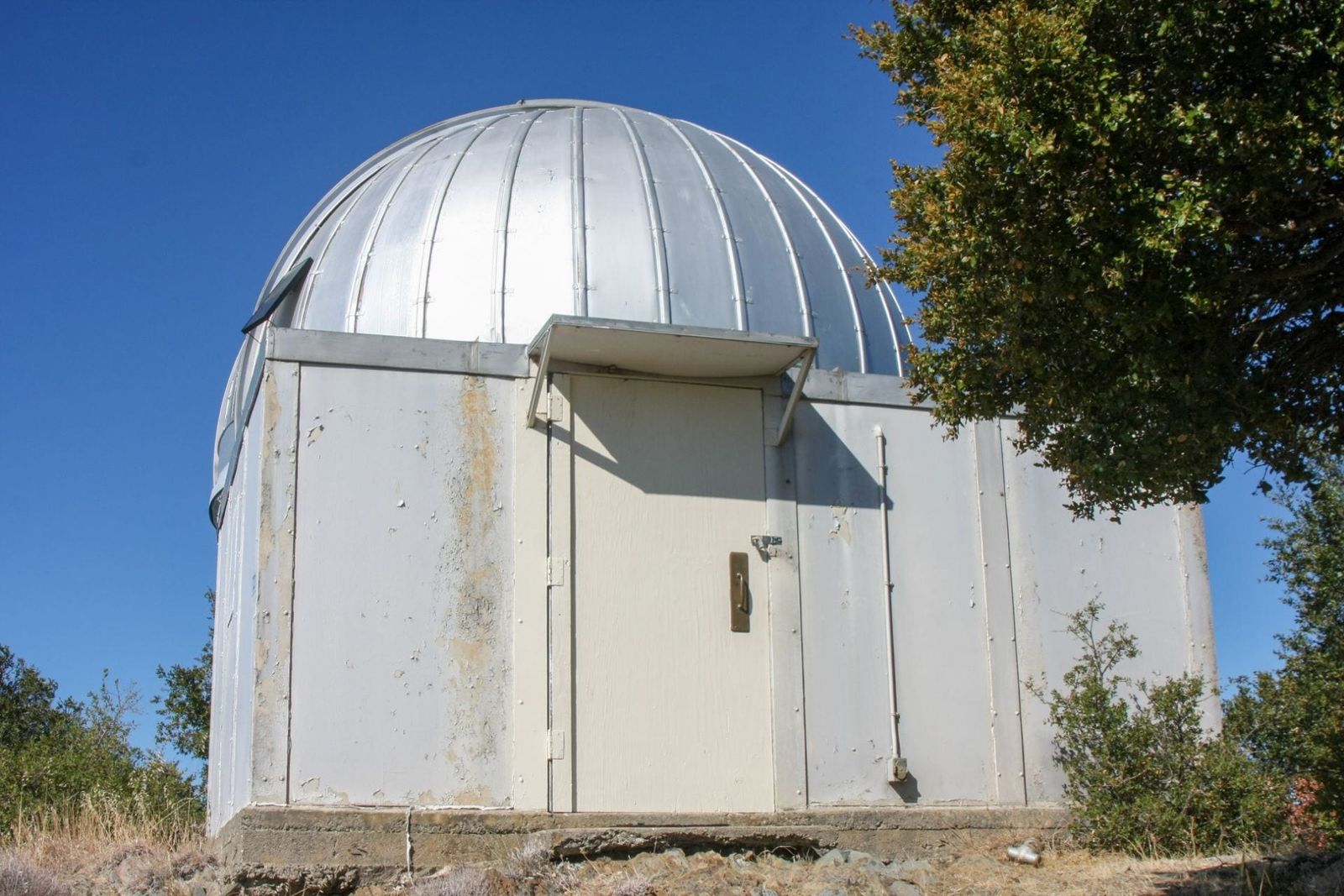 White observatory building with a silver dome under a blue sky