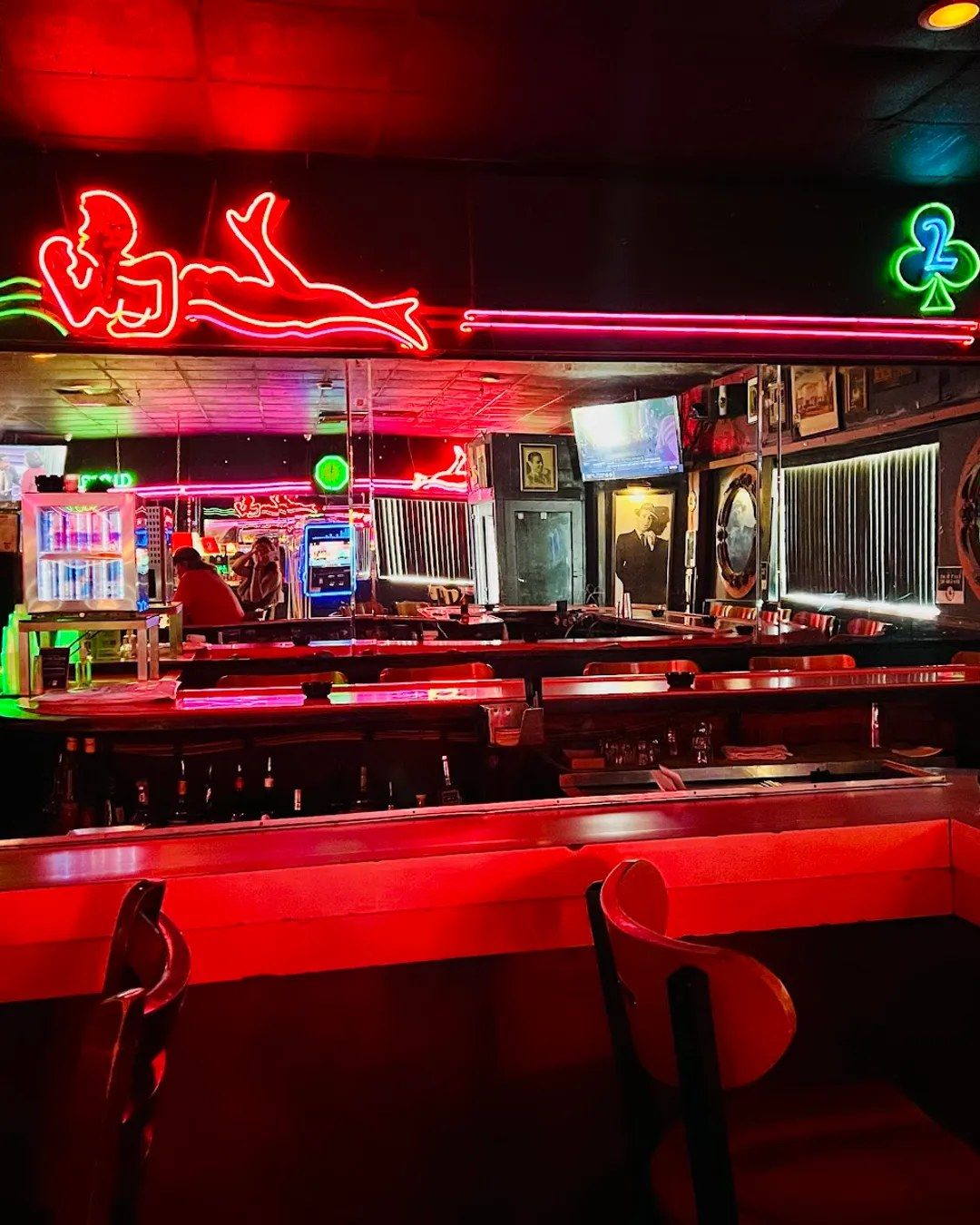 Bar interior with red booths and neon signs glowing above the counter