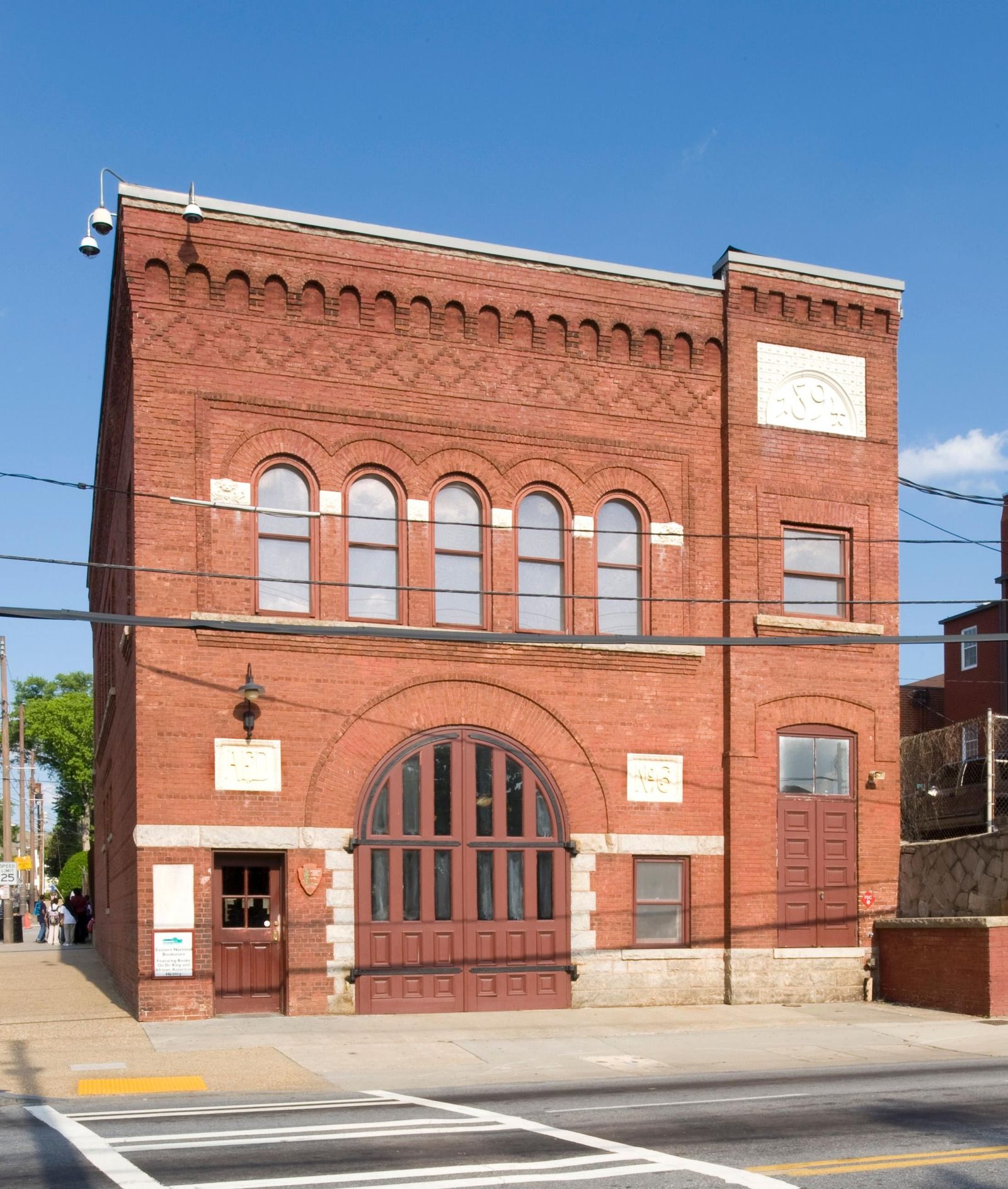 A red brick historic fire station building on a street corner under a blue sky