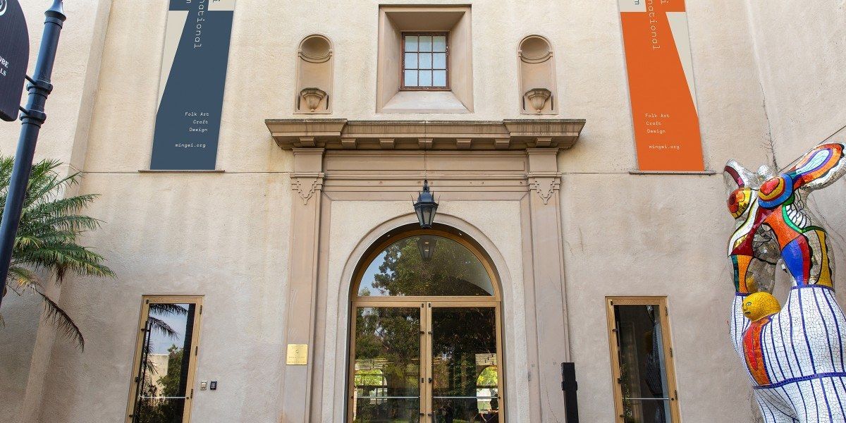 An arched stone museum doorway under a building facade with colorful banners.