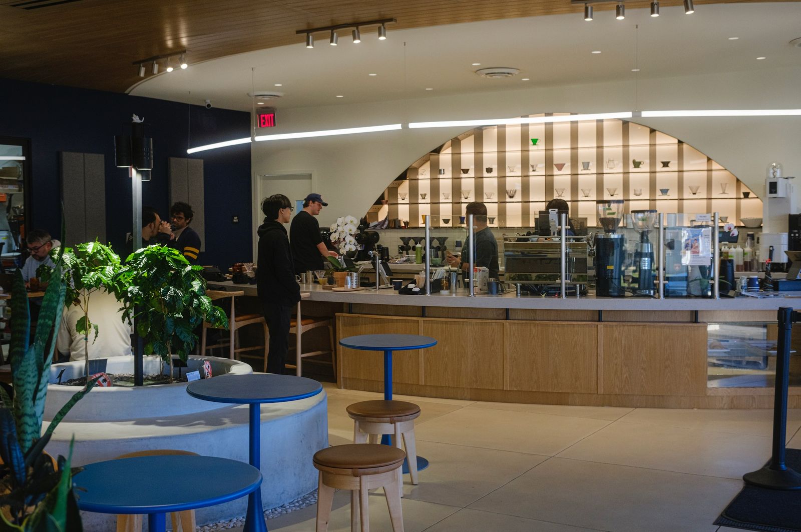 Cafe interior with a long counter, round blue tables and stools