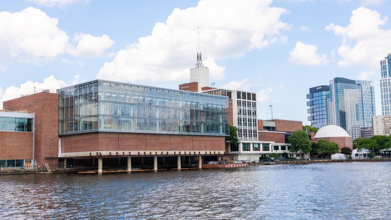 The museum's glass and brick building beside the Charles River basin on a sunny day