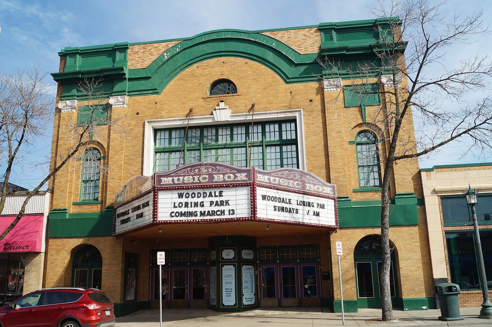 The theater's yellow brick facade with green trim, a marquee and arched window above the entrance.