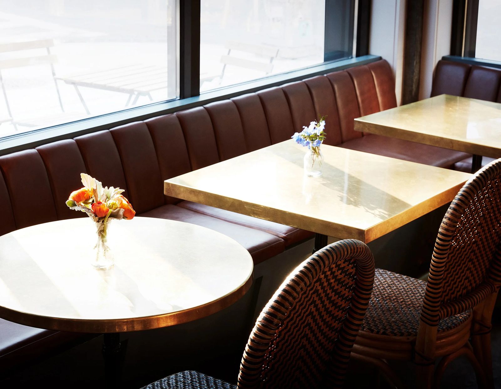 Red leather booths and round tables beside a large window