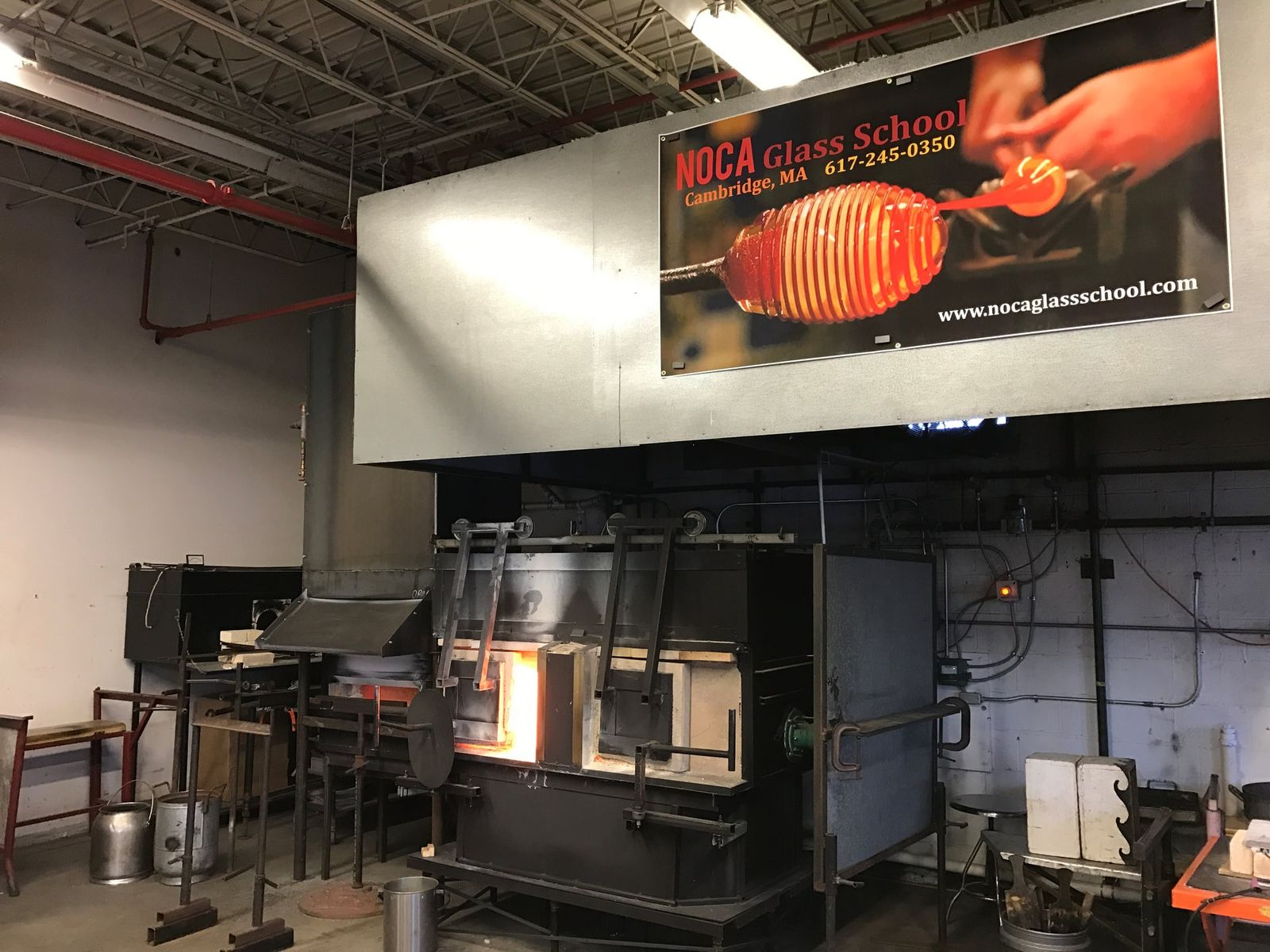 The glassblowing studio with a furnace glowing under a wall banner