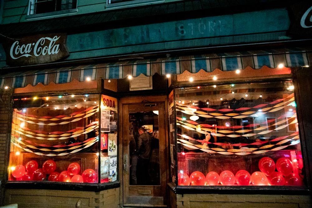 Night-time storefront with a lit window display and a Coca-Cola sign