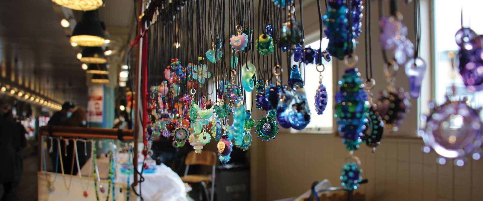 Hanging glass ornaments in many colors above a market stall arcade.