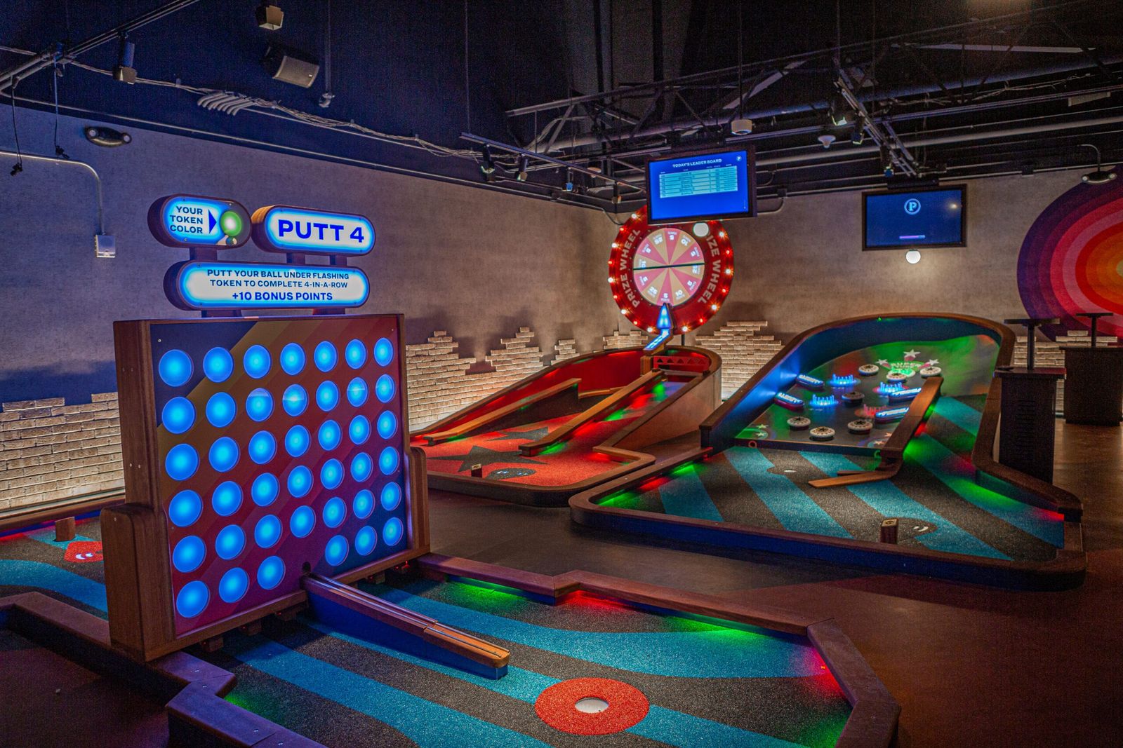A neon-lit mini golf course with a giant Connect Four and bar