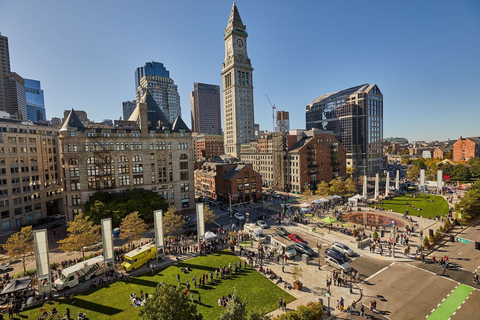 Aerial view of a downtown park with lawns and white pillars beside a tall clock tower