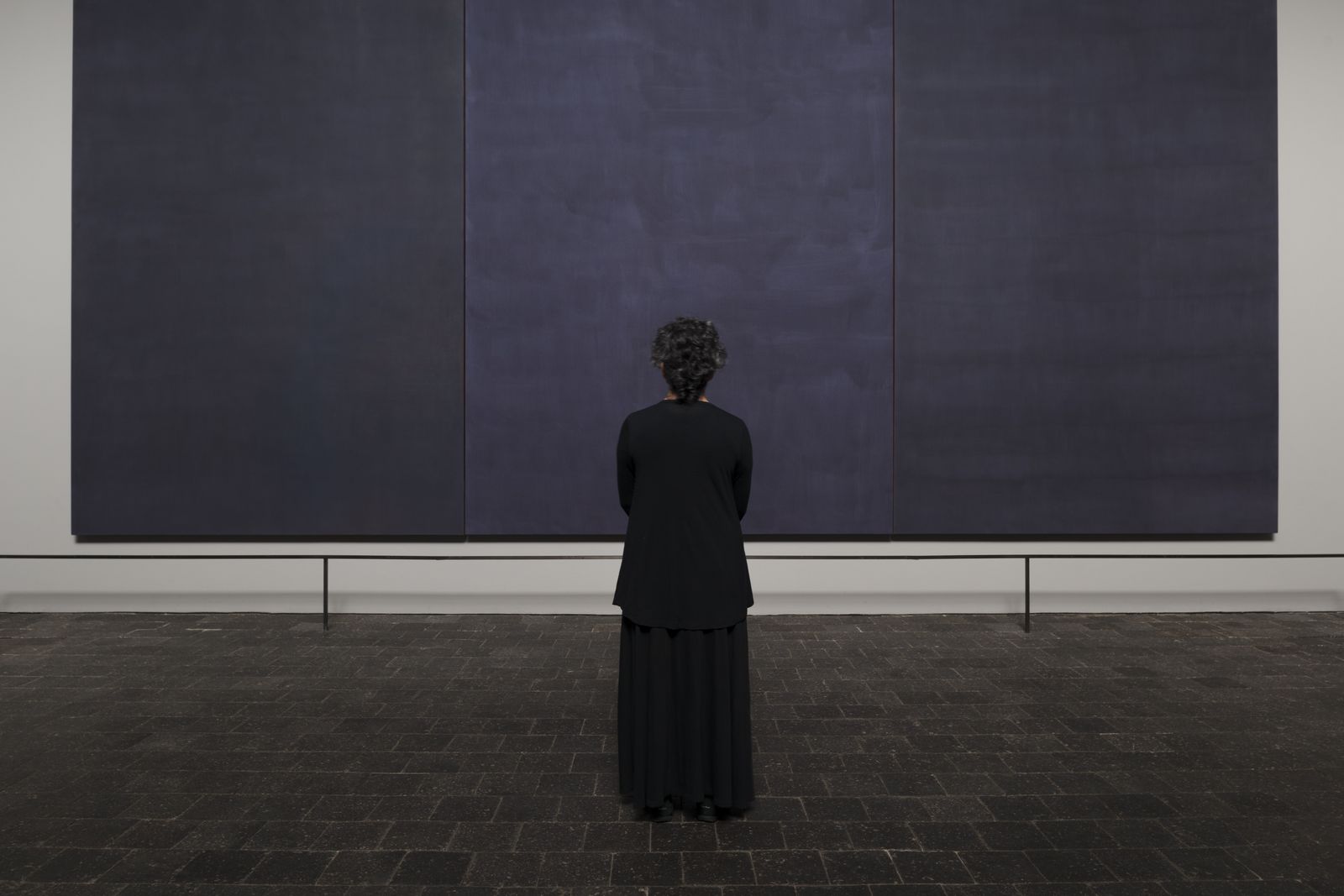 A lone visitor standing before the large dark Rothko panels inside the chapel