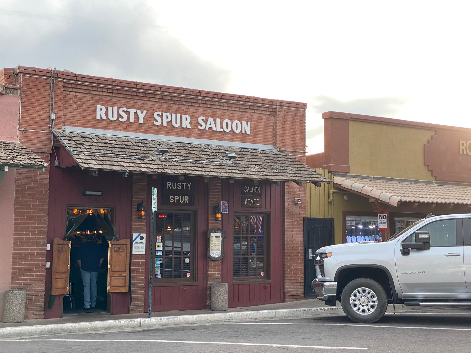 Brick storefront with a Rusty Spur Saloon sign and swinging saloon doors