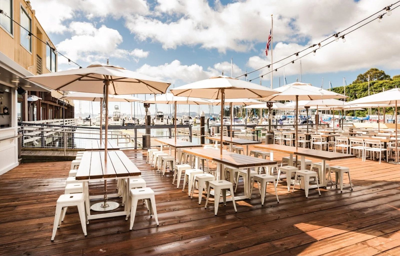 Waterfront deck with picnic tables and market umbrellas beside the marina