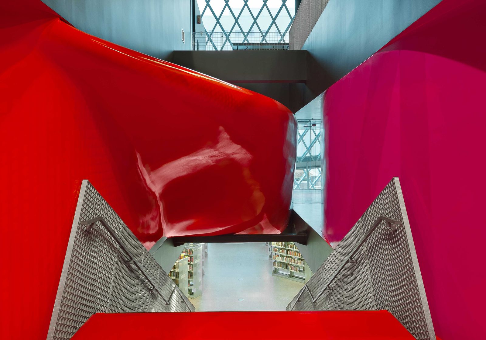 Looking up through the library's atrium, with red and magenta panels framing a view of glass and steel above.