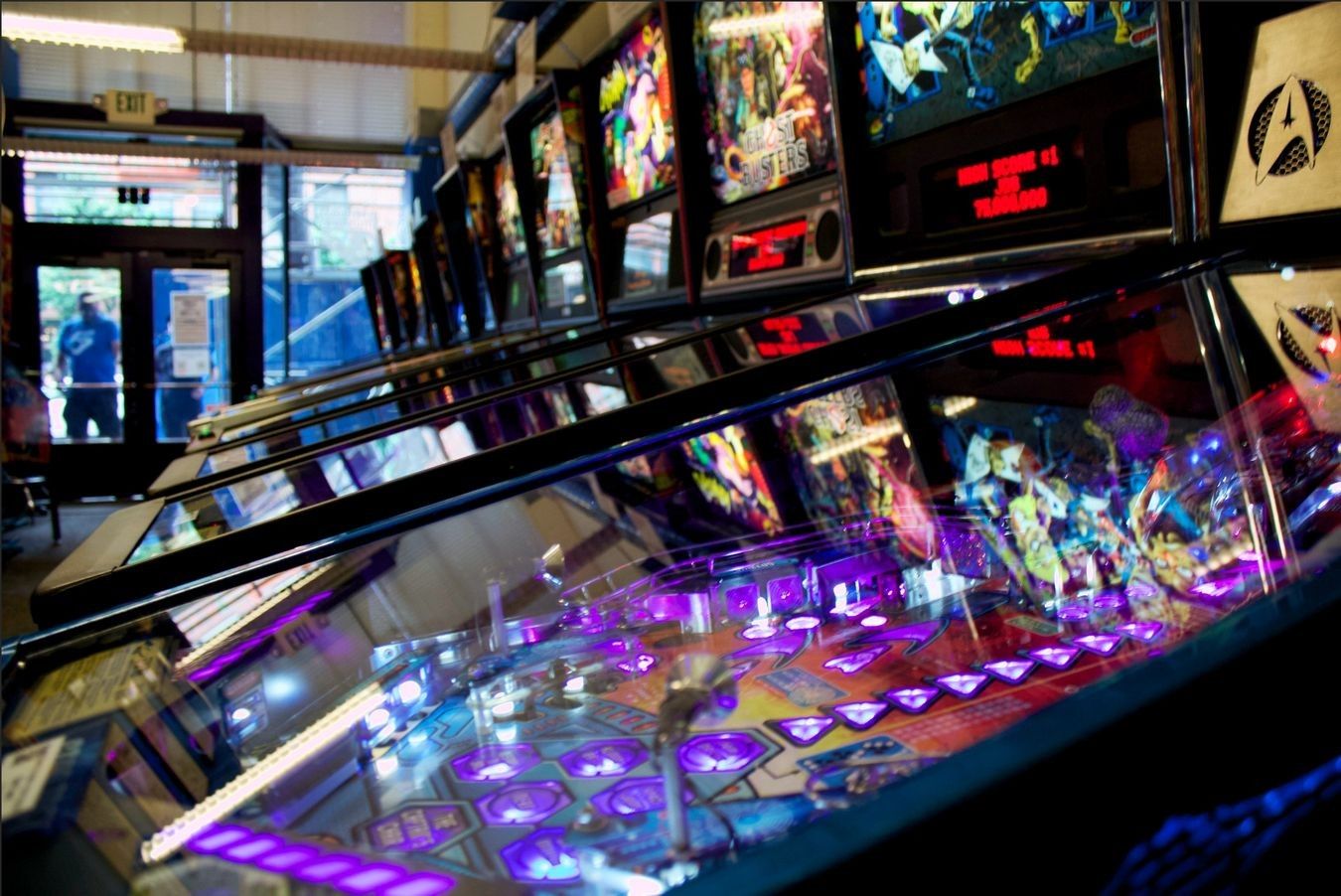 Rows of lit pinball machines in a dim room.