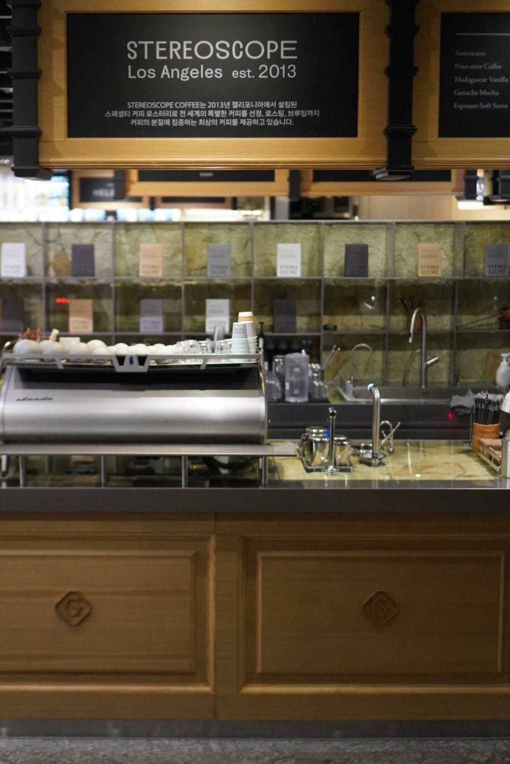 An espresso bar with a glass pastry case and a sign reading Stereoscope Los Angeles.