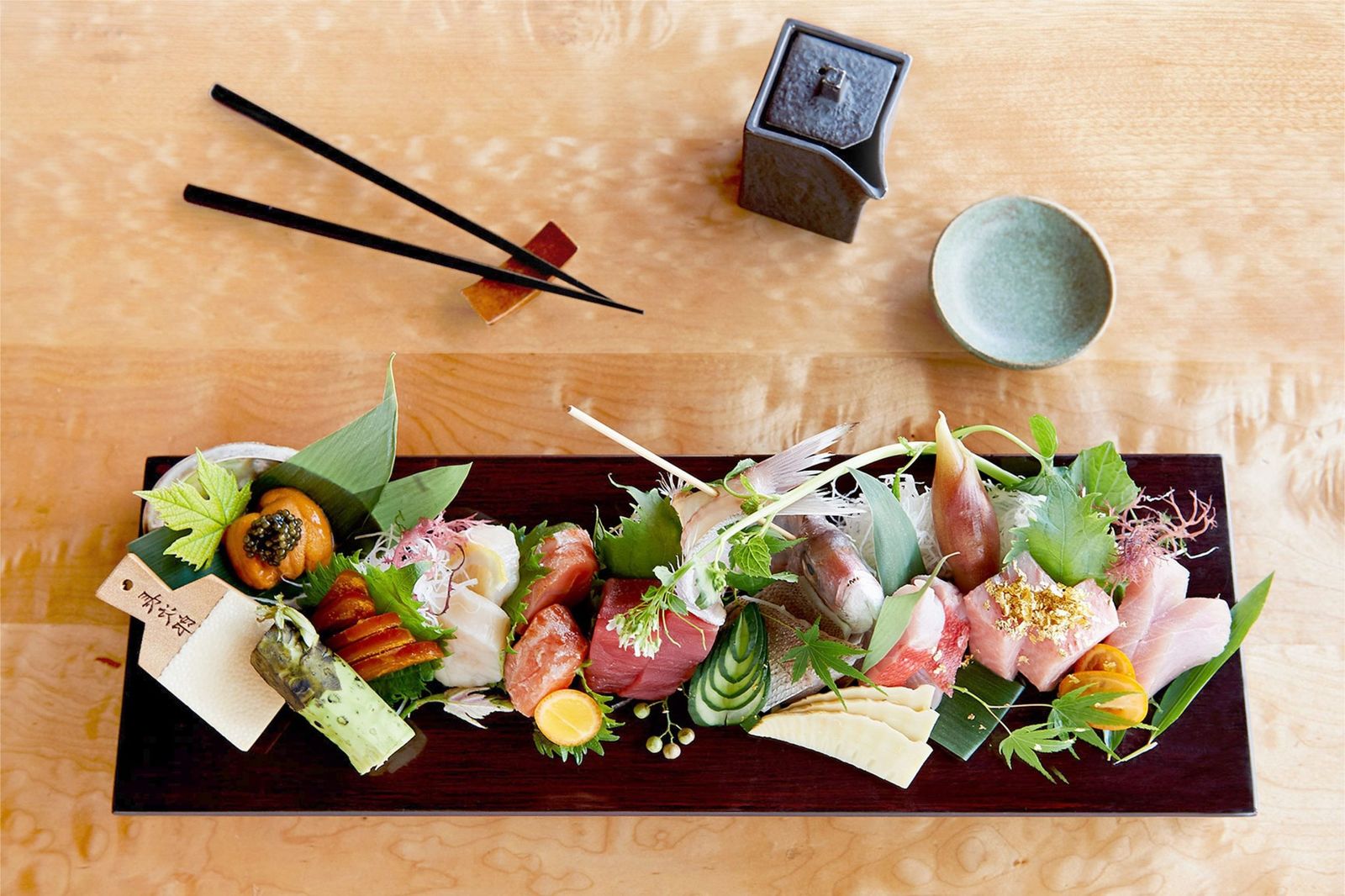 Sashimi platter with garnishes and chopsticks on a wooden table