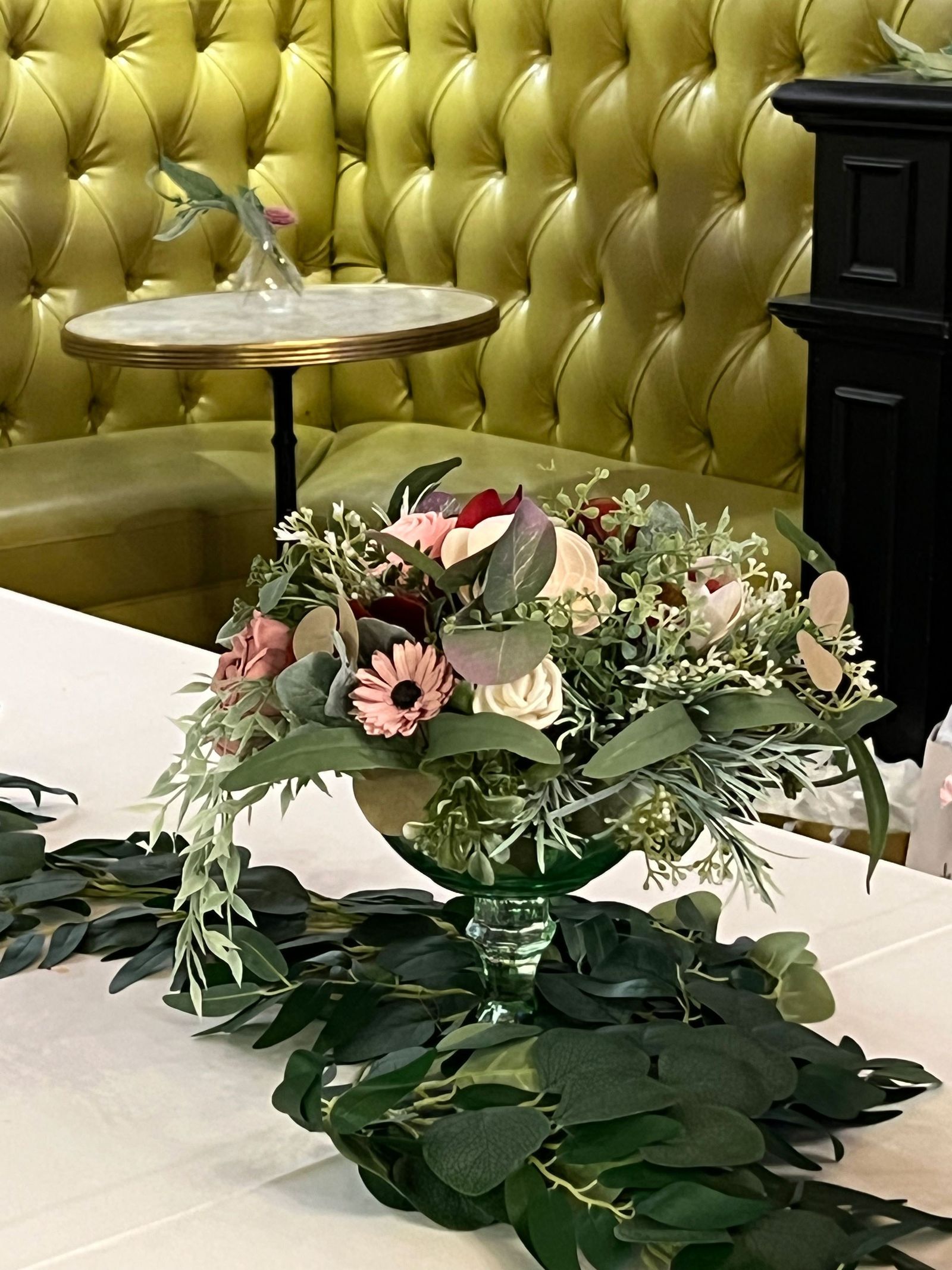 Yellow tufted banquette beside a table with a flower arrangement