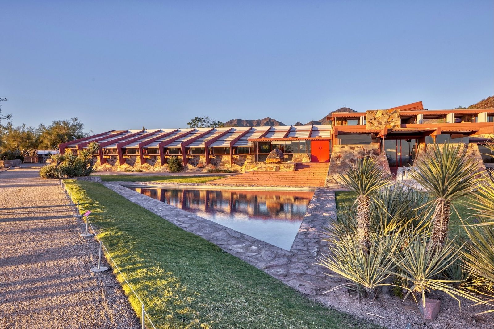The low desert-stone buildings of Taliesin West beside a reflecting pool at golden hour