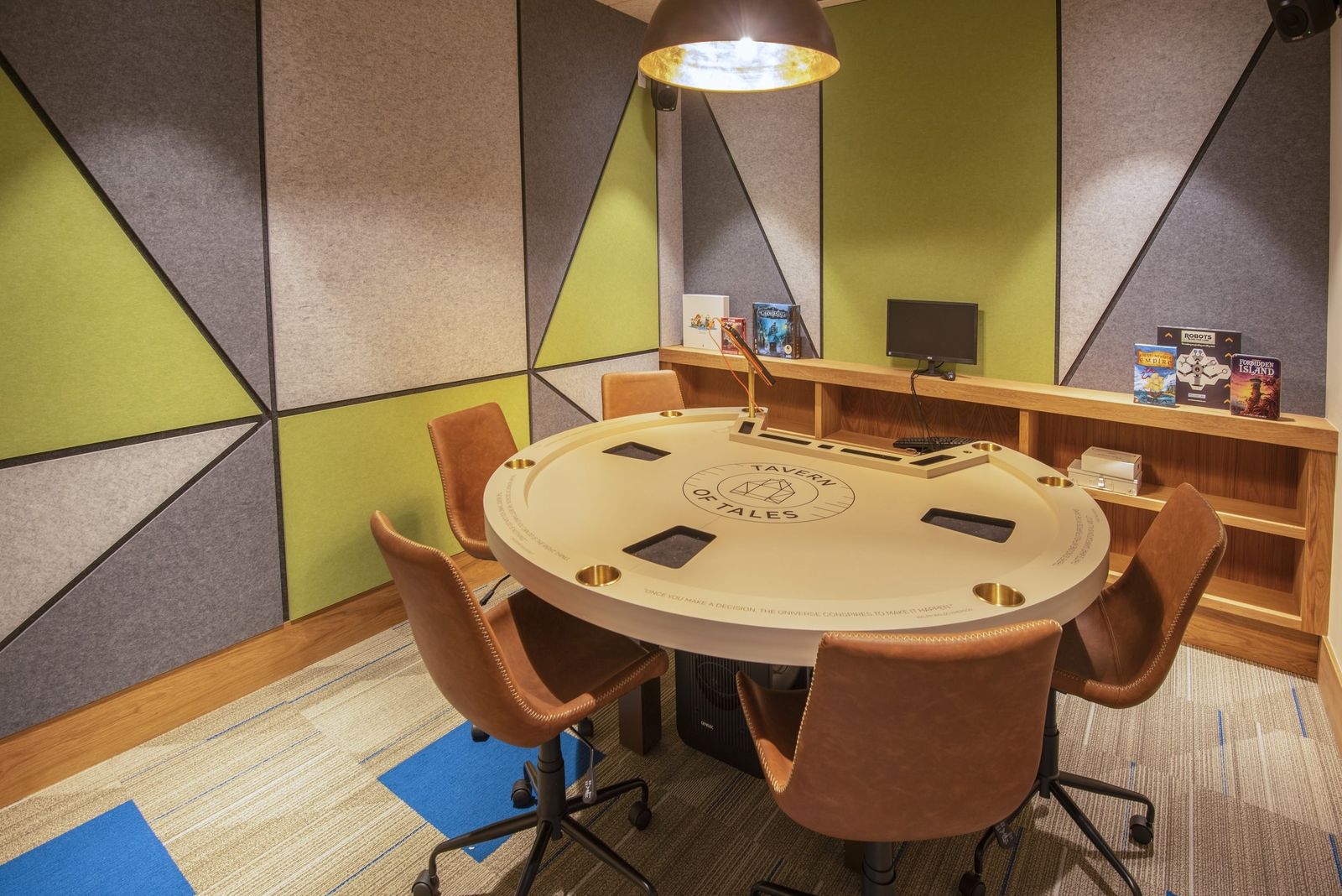 A round game table with chairs in a room with colorful acoustic wall panels